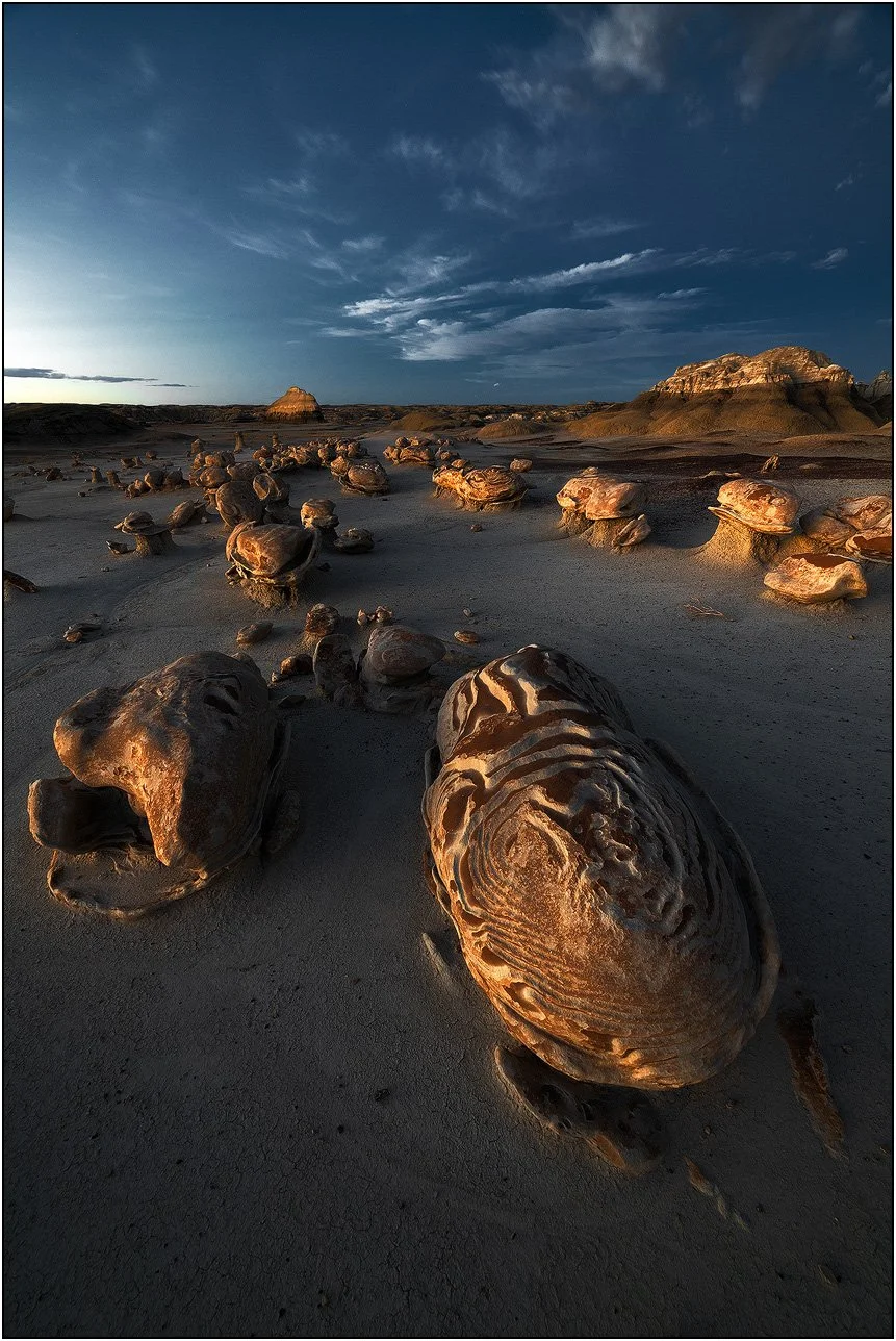 Eroded rock formations in desert badlands under low-angle sunlight