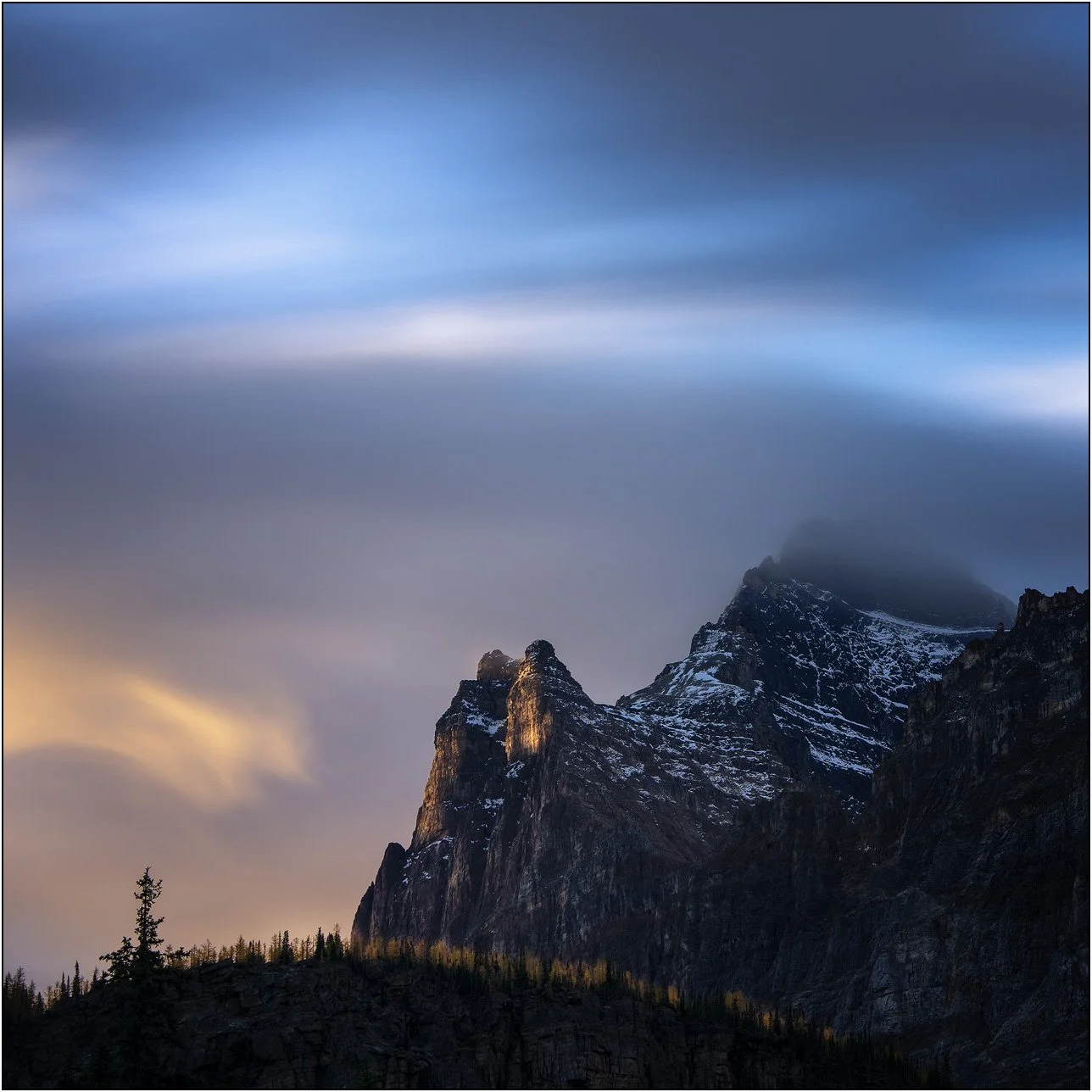 Long exposure photograph of cloud and peaks of the Canadian Rockies.
