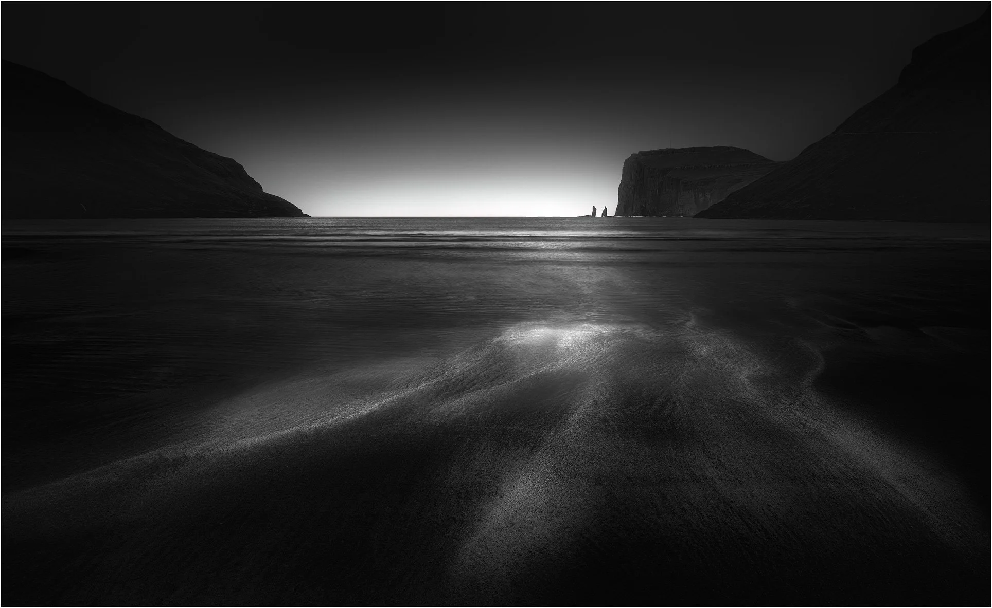 Black and white moody seascape image of Saksun beach, Faroe Islands.