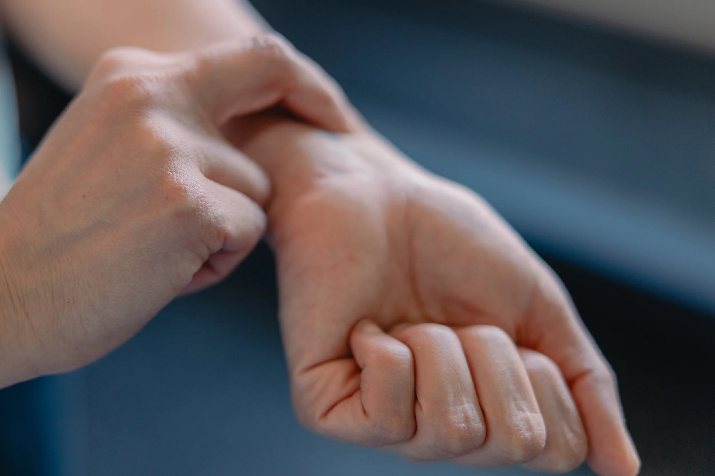Close-up of a person's hand gently holding a child's hand.