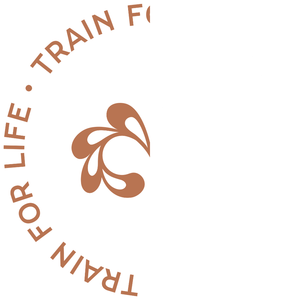 A circular logo with a black background, featuring brown and white floral-like designs in the center. Text around the circle reads 'Training for Life. Train for Life. For Life. Training for Life.'