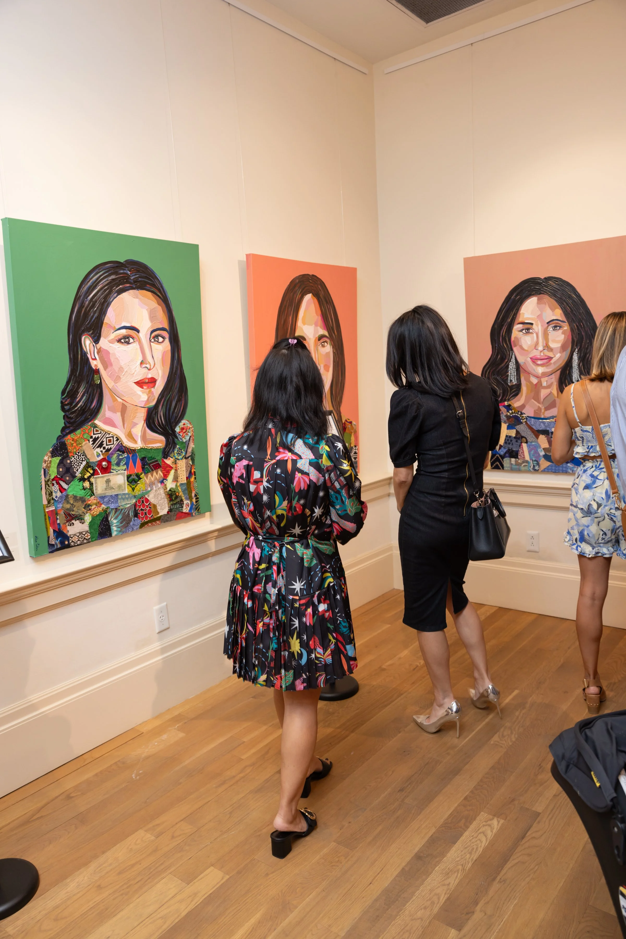 People viewing colorful portrait paintings of women in an art gallery.