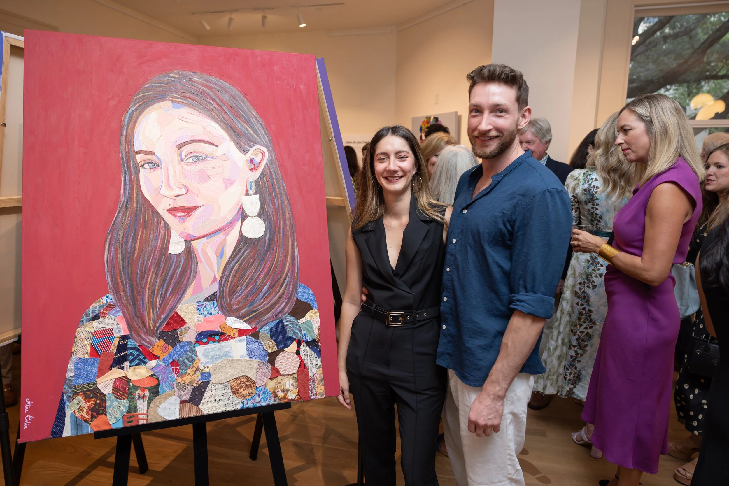 People attending an art gallery exhibit, viewing a colorful portrait painting of a woman with long hair, earrings, and a calm expression, with multiple people engaged and observing in the background.