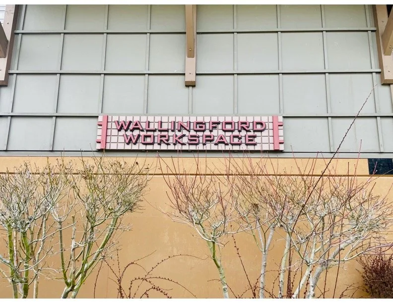 Sign that reads 'Wallingford Workspace' mounted on a light green wall, with leafless trees in the foreground.