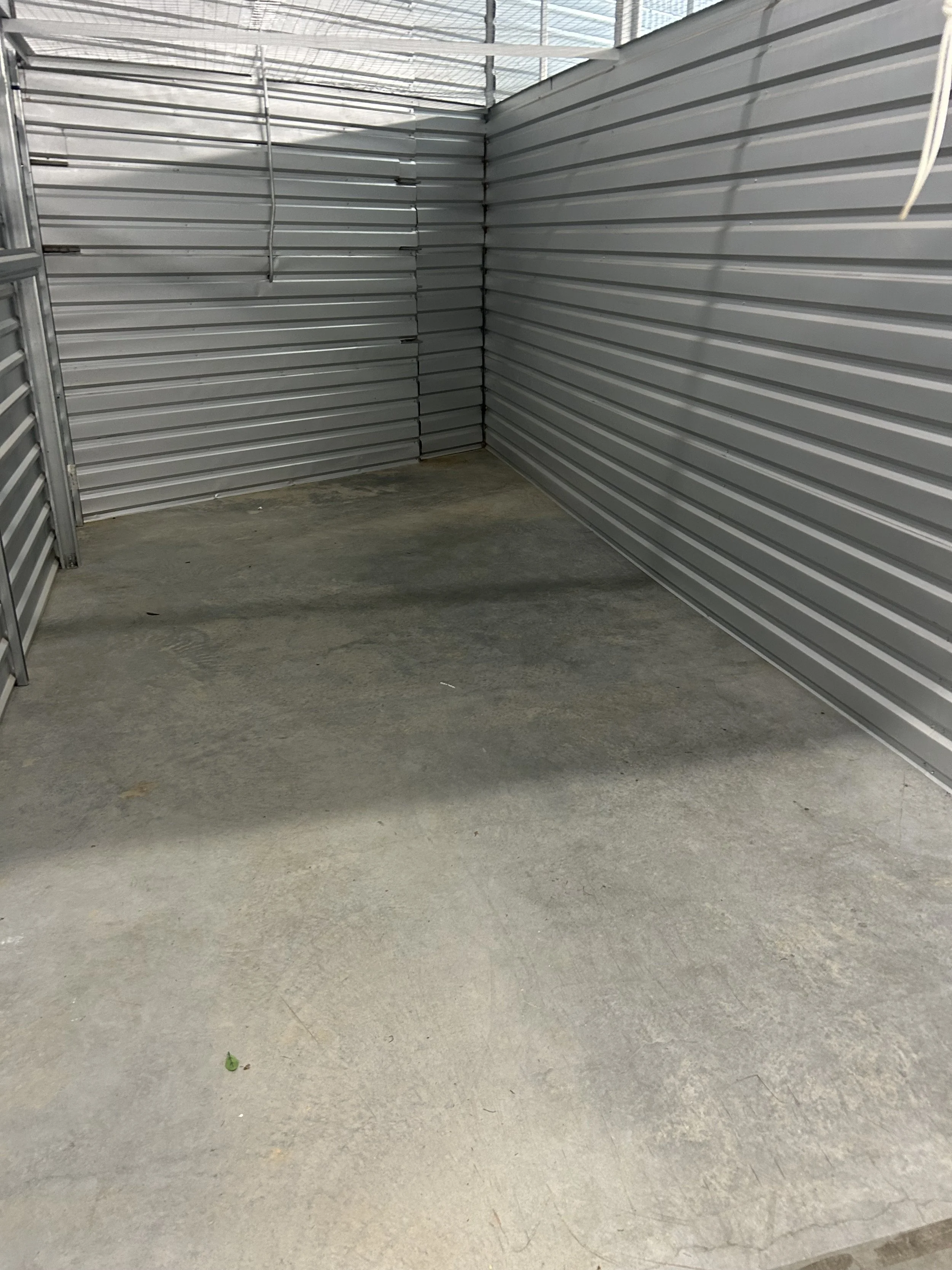 Empty storage unit with metal walls and concrete floor.