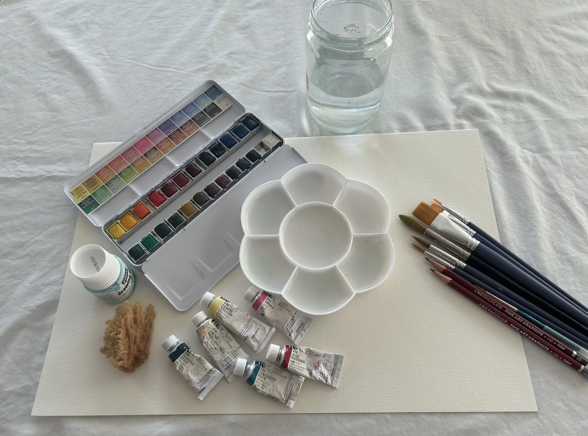 watercolour colours palette water jar, brushes, paper and mixing tray