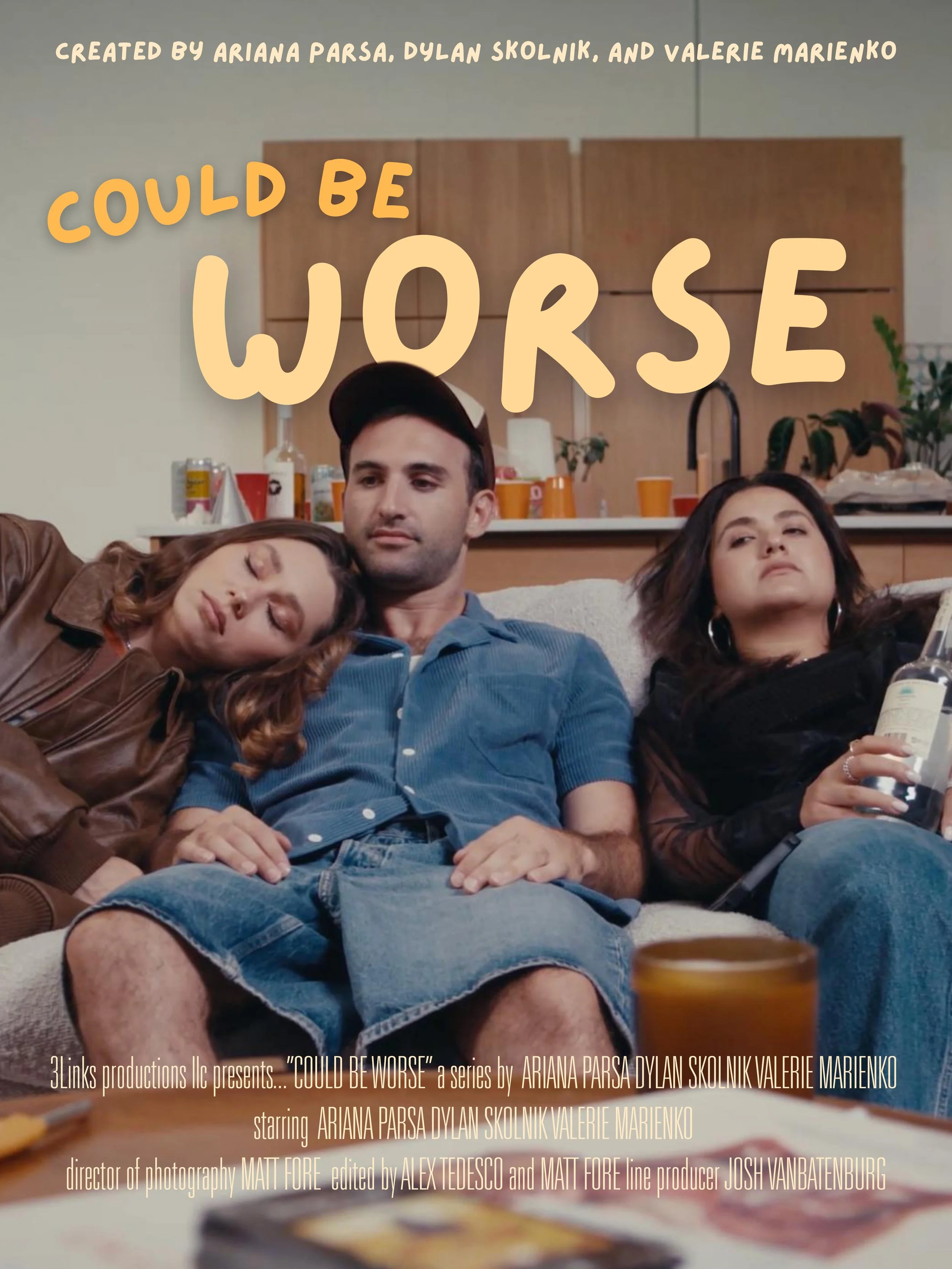 Three people sitting on a couch with tired or bored expressions, one woman resting her head on a man's shoulder, another woman holding a drink, in a cluttered room with cups and bottles in the background. Overlaid text says 'Could Be Worse'.