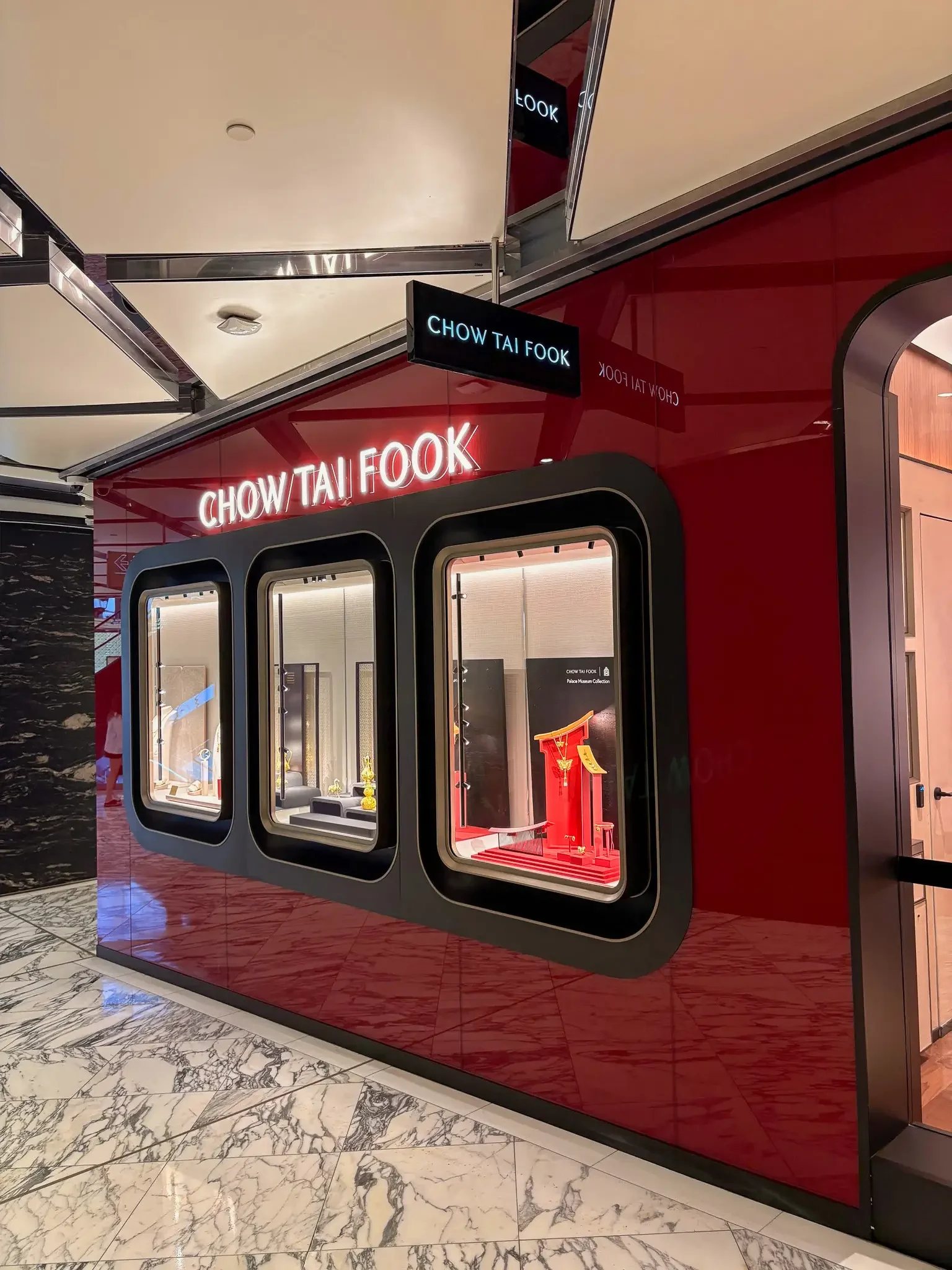 Display window showcasing jewelry at Chow Tai Fook store with illuminated sign and red background
