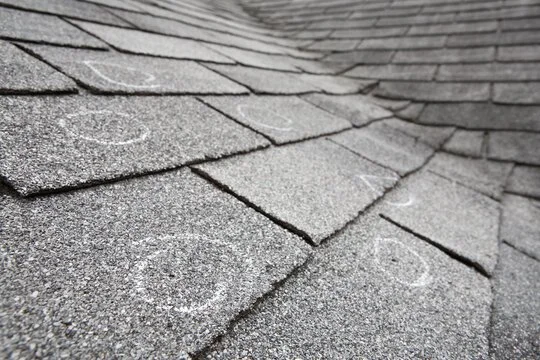 Close-up of a shingled roof with some chalk markings.