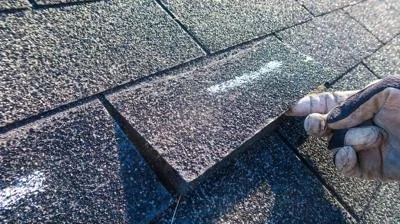 Person wearing gloves drawing with chalk on pavement.
