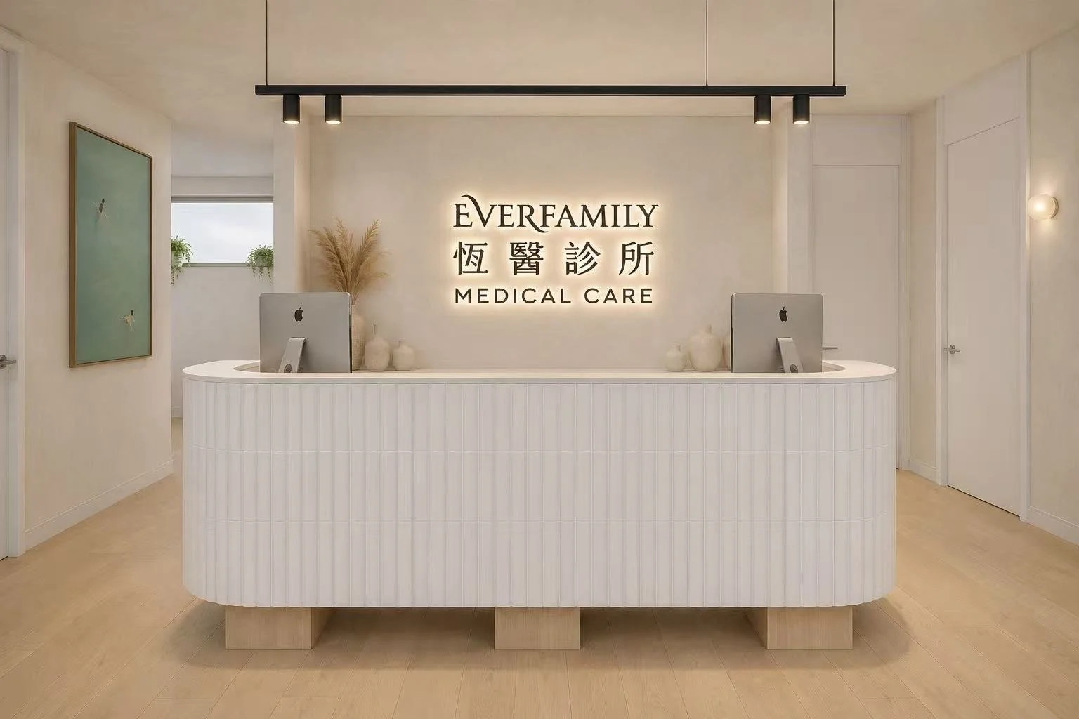 Reception area at Always Family Medical Care with a white curved counter, two Apple computers, decorative vases, and a backlit sign displaying the clinic's name in English and Chinese characters.