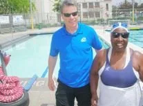 Two people, one man and one woman, standing next to a swimming pool outdoors.