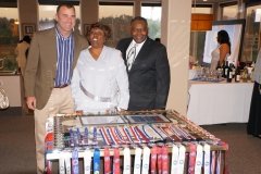 Three people standing behind a table with an assortment of jewelry.