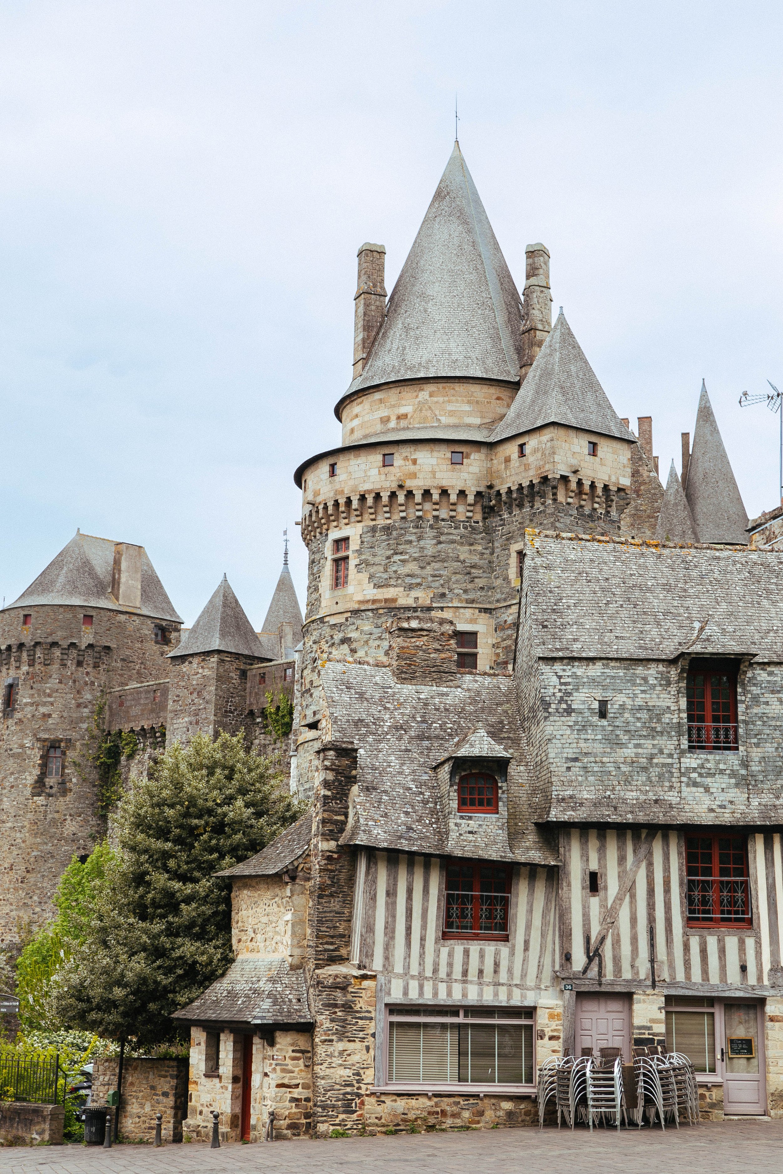 A historic stone castle with multiple towers and conical roofs, featuring a mix of medieval and rustic architecture.