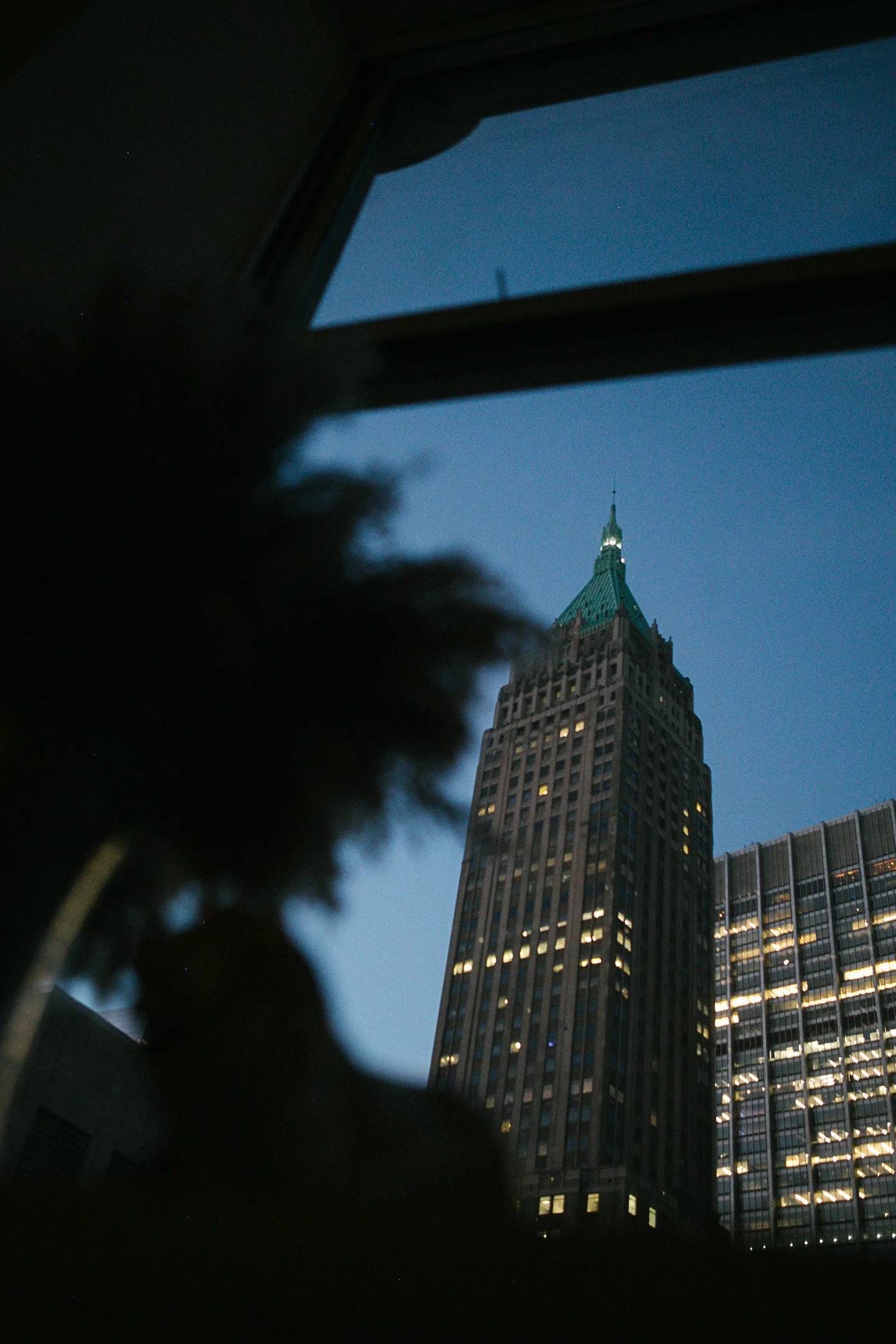The Empire State Building viewed from inside a room, seen through a window at dusk or evening.