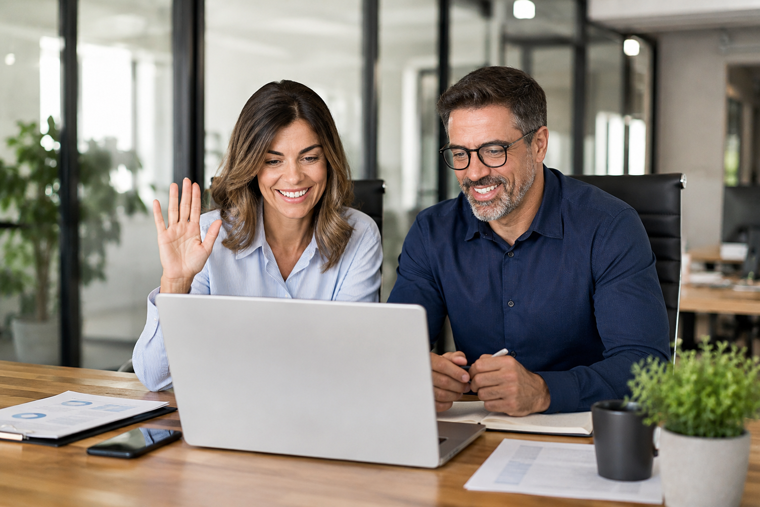 two business owners sitting in front of a computer screen appearing to be on a video conference.