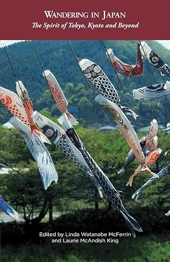 Book cover titled "Wandering in Japan: The Spirit of Tokyo, Kyoto and Beyond," featuring colorful koinobori (carp streamers) flying against a backdrop of trees and a mountain in Japan. Book & Author Publicity by Quatrain PR.