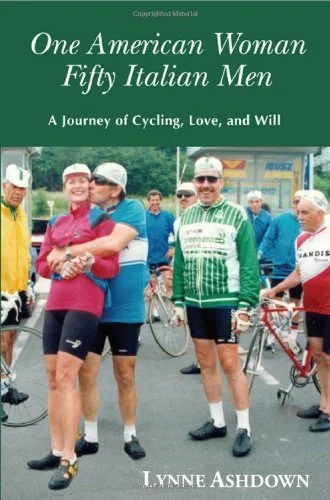 Book cover titled 'One American Woman Fifty Italian Men: A Journey of Cycling, Love, and Will' by Lynne Ashdown, featuring a group of older men and women in cycling gear at a gathering, outdoors.