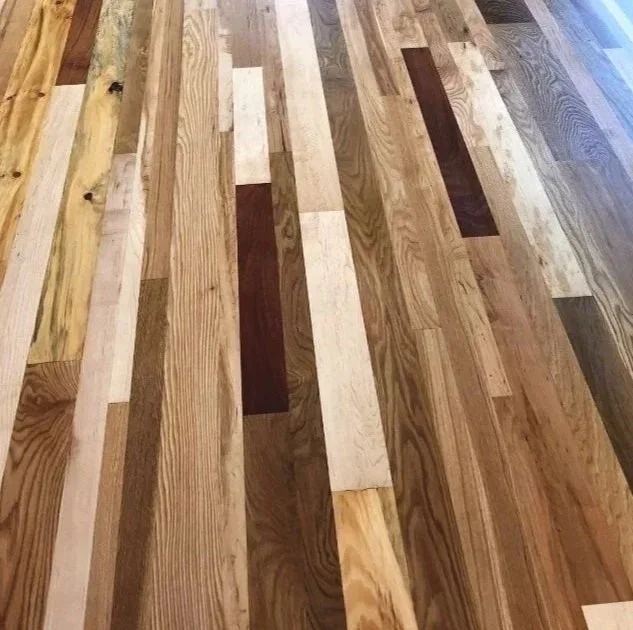 Close-up of a wooden flooring with various shades of brown and tan hardwood planks arranged in a staggered pattern.