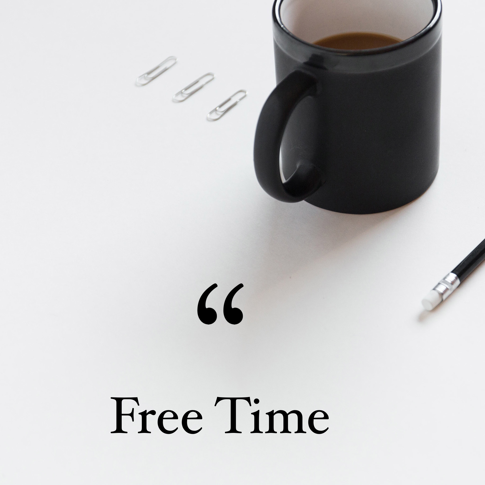 A black mug filled with coffee, three paper clips to the left of the mug, and part of a pen at the bottom right corner, with the partially visible text reading 'Free Time' on the white surface.