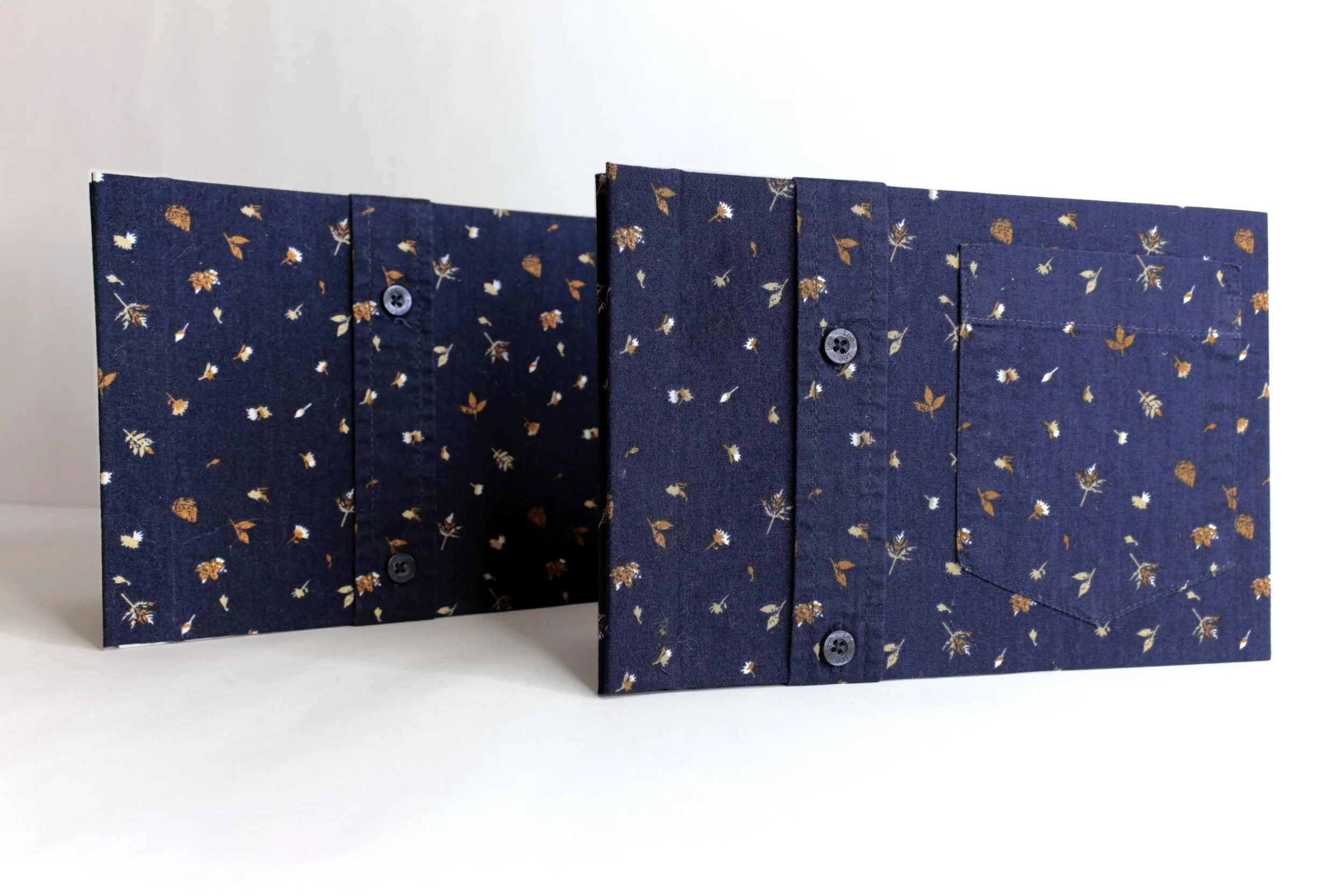 Folded navy blue fabric with small floral pattern and buttons wrapped as book cloth.