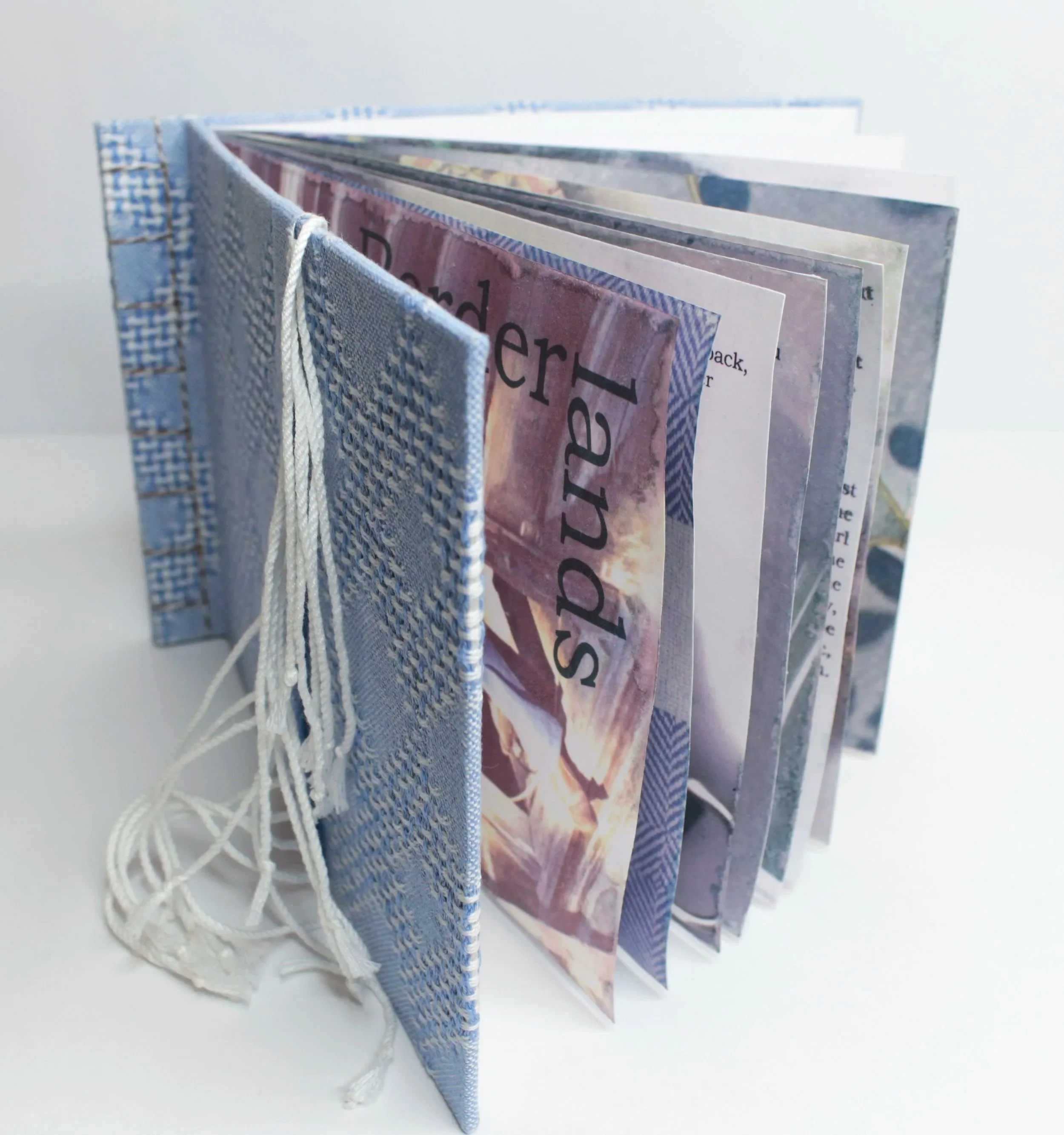 A fabric bound book with several pages, held together by a string, displaying text and images.