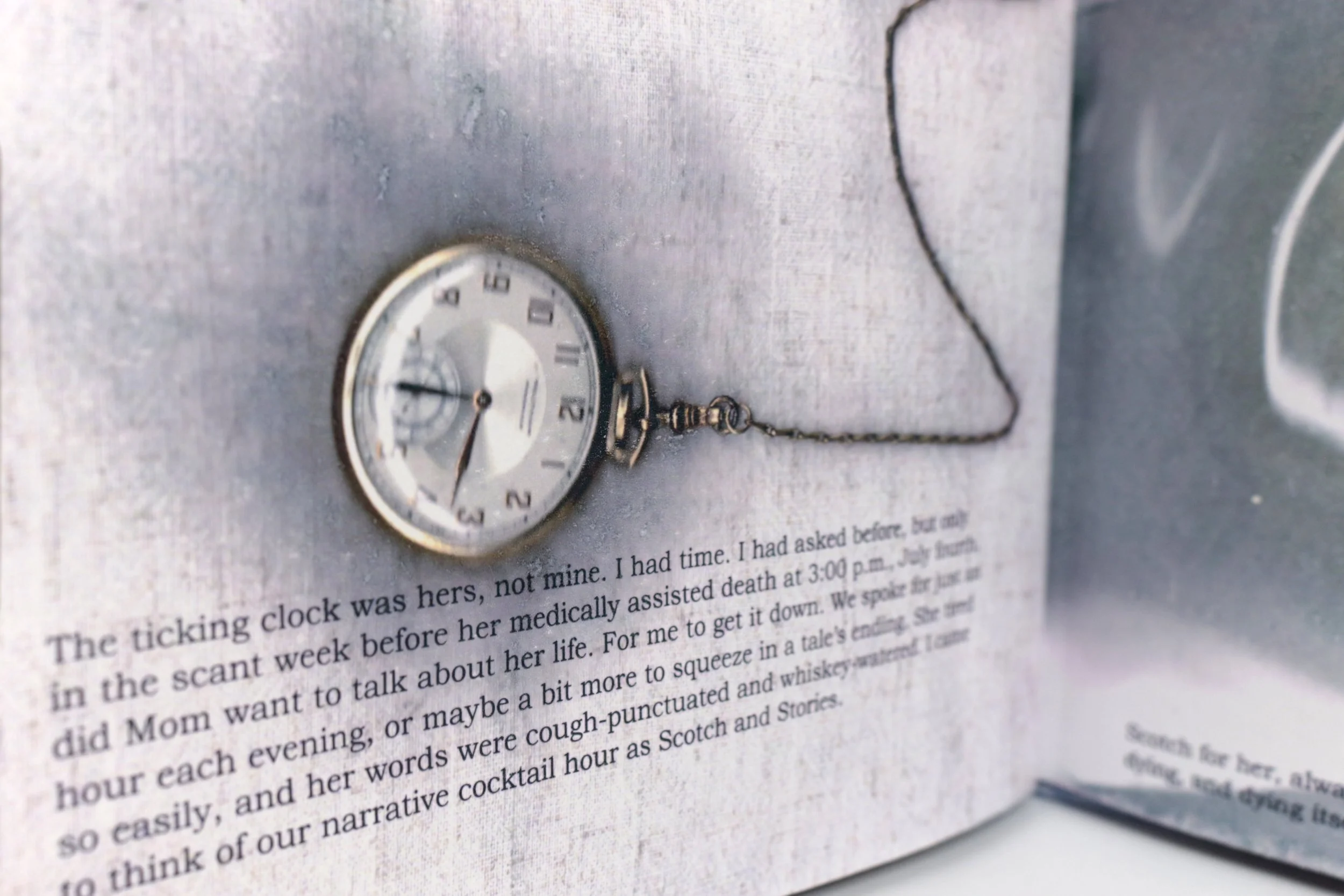Close-up of a pocket watch with a chain resting on a page of a book or magazine, showing the time as approximately 9:37, with text visible beneath.