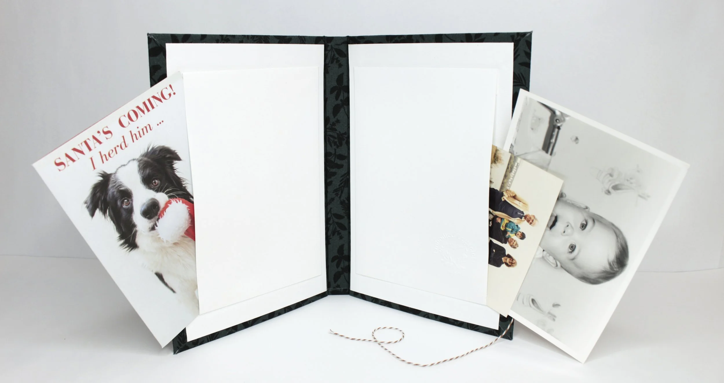 Open photo album with blank pages, having three photographs inside and a card with a dog and text about Santa