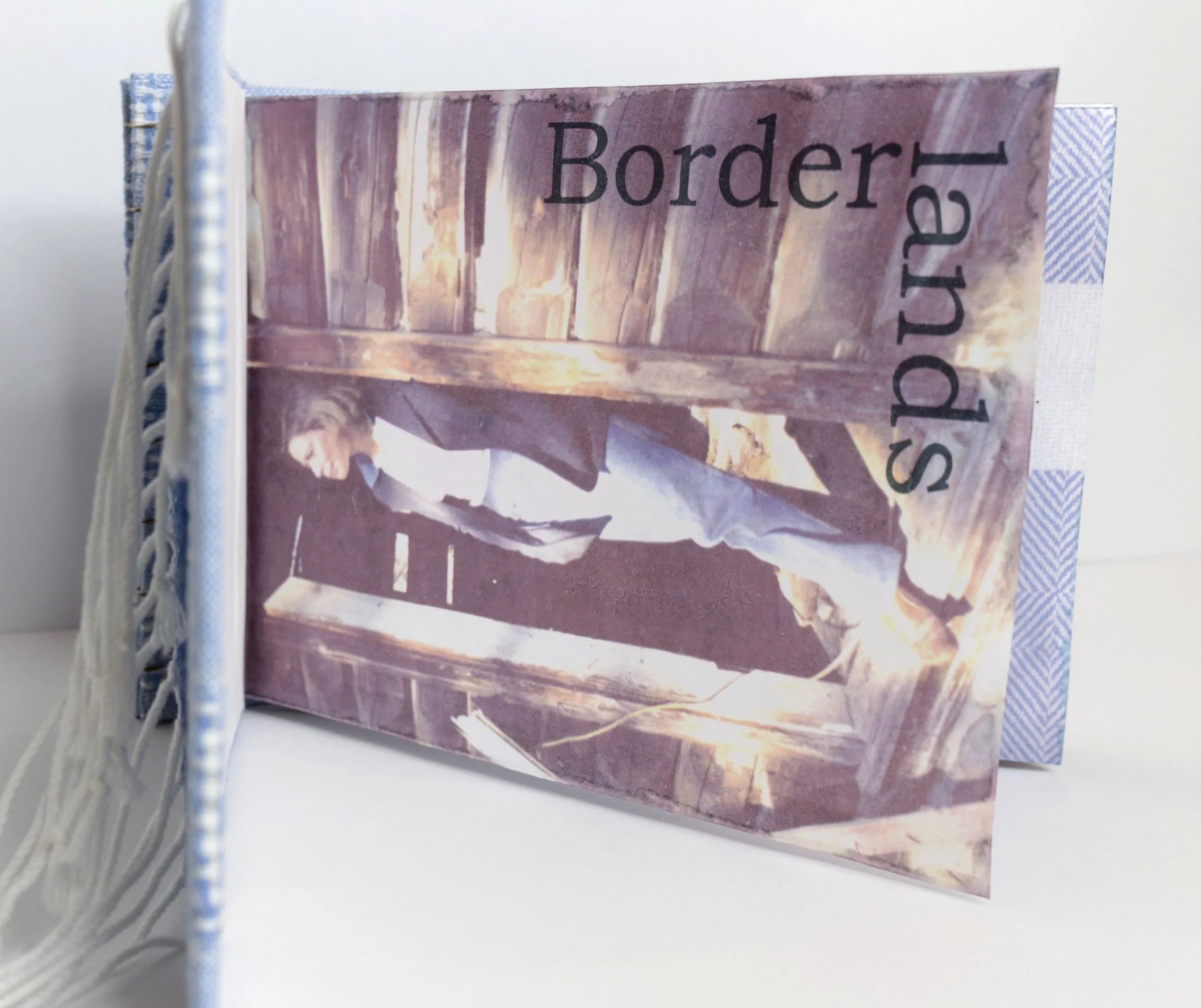 Artwork with the words 'Border Lands' and an image of a person standing in a barn or wooden structure.