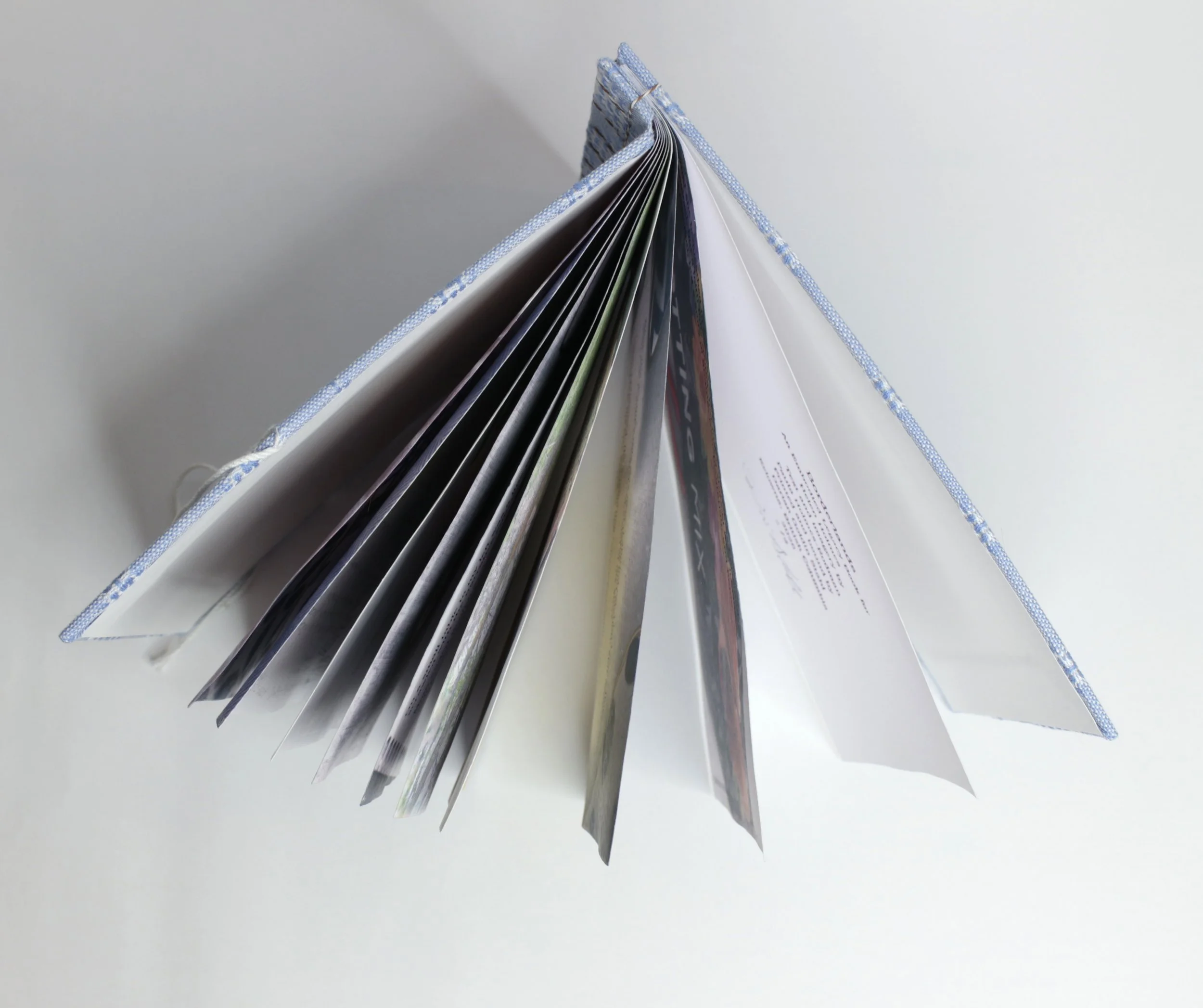Open book, viewed from the top, showing pages with images and text on a white surface.