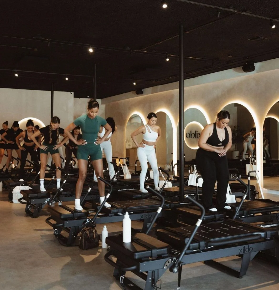 Women participating in a fitness class using mini step machines in a gym.