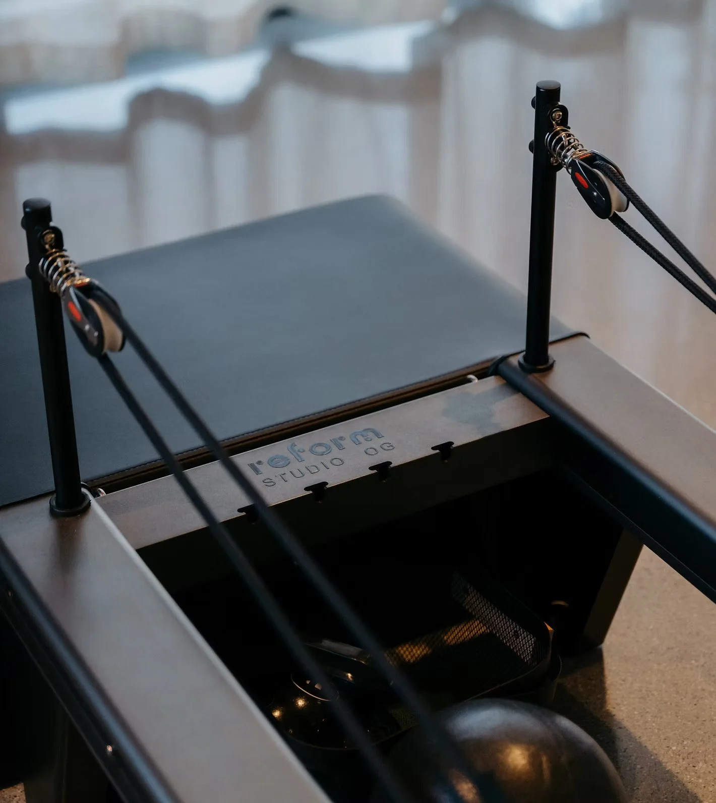 A close-up of a metal frame attached to a treadmill, with the brand name 'reforna' visible on the side, set against a background of blurred indoor setting.