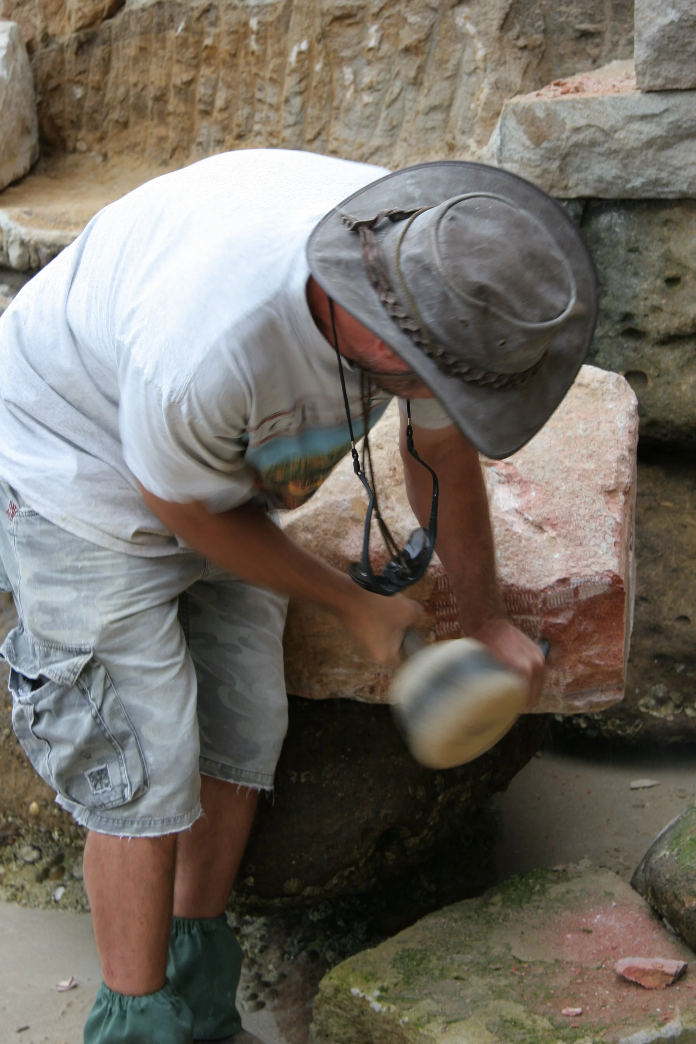 Worker shaping the stone for a wall.JPG