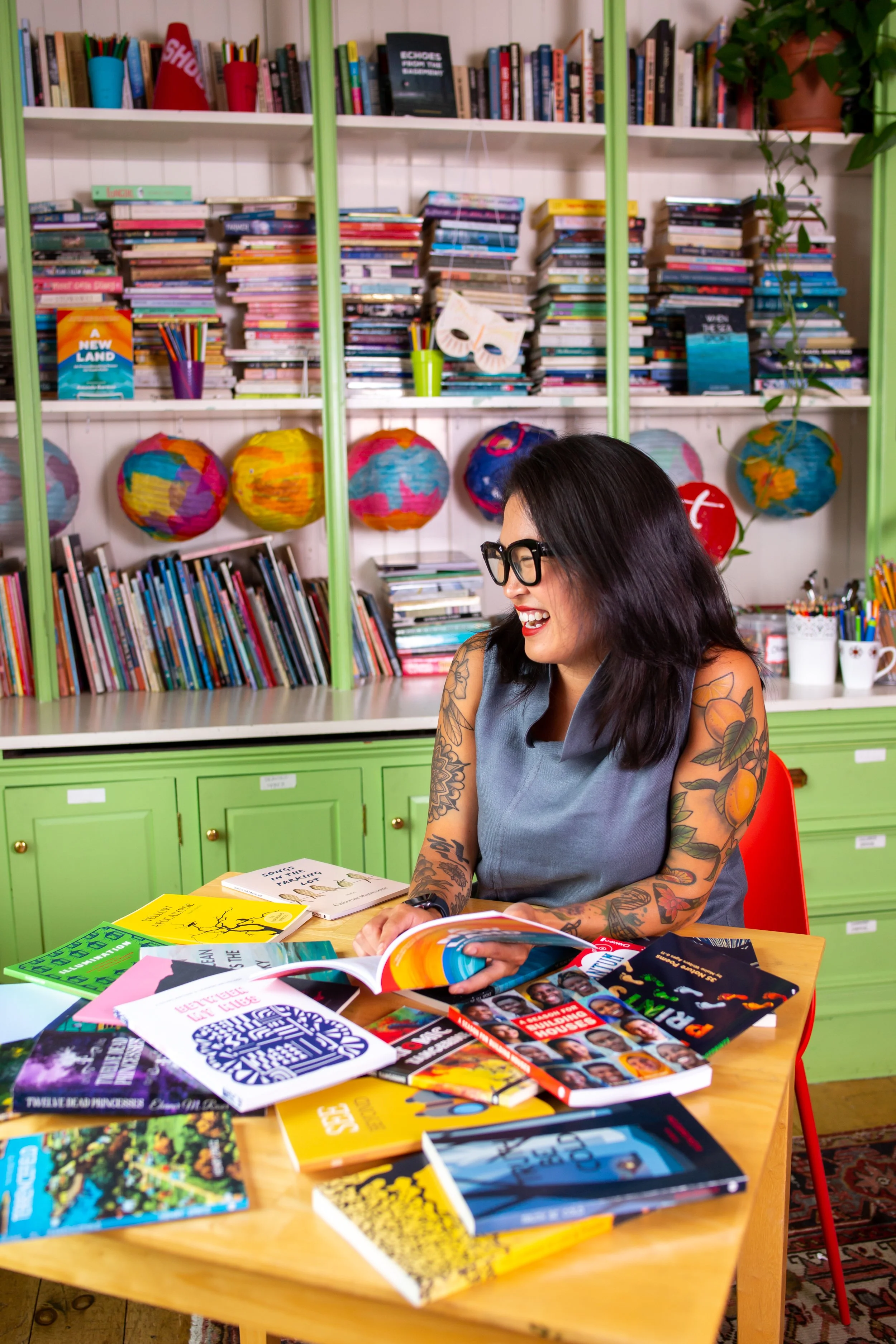 Kristina Powell Executive Director The Telling Room sits at color desk filled with books