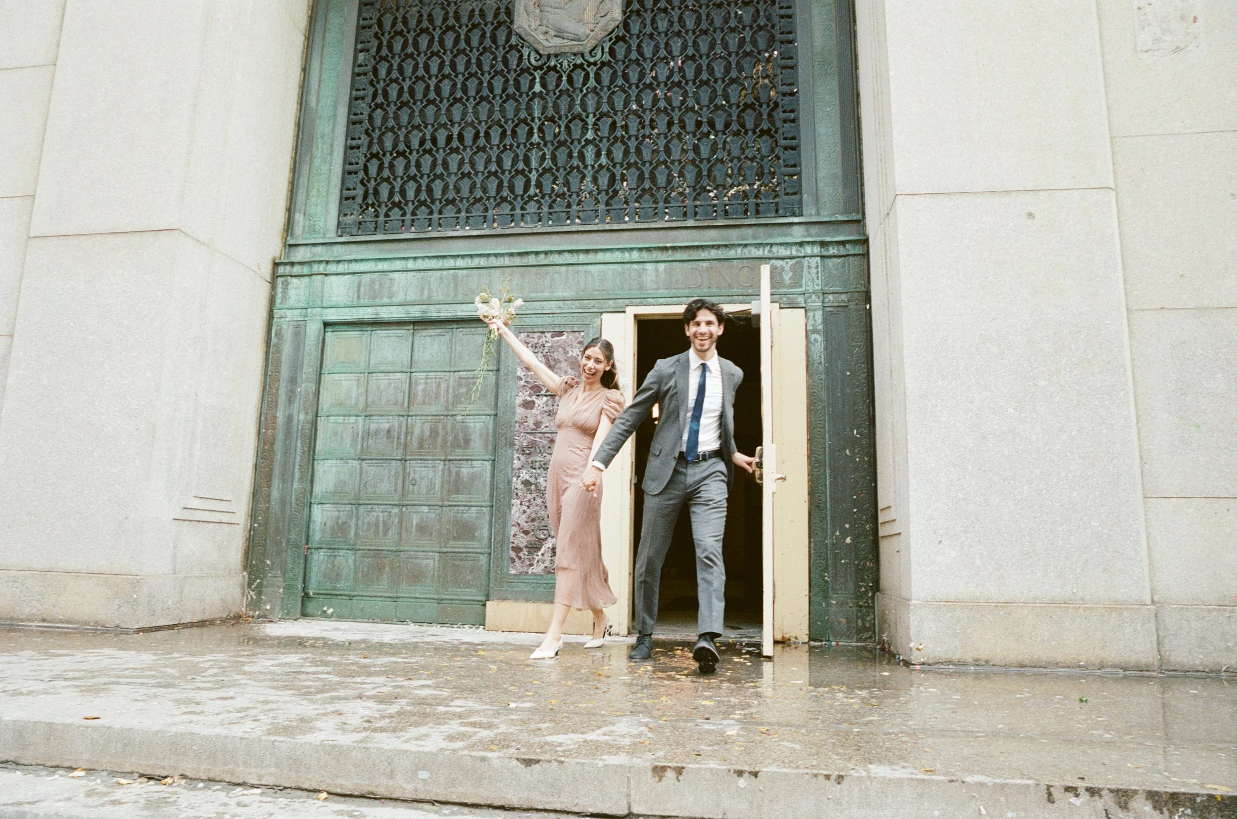 Couple exiting Manhattan Marriage Bureau after NYC courthouse wedding on film