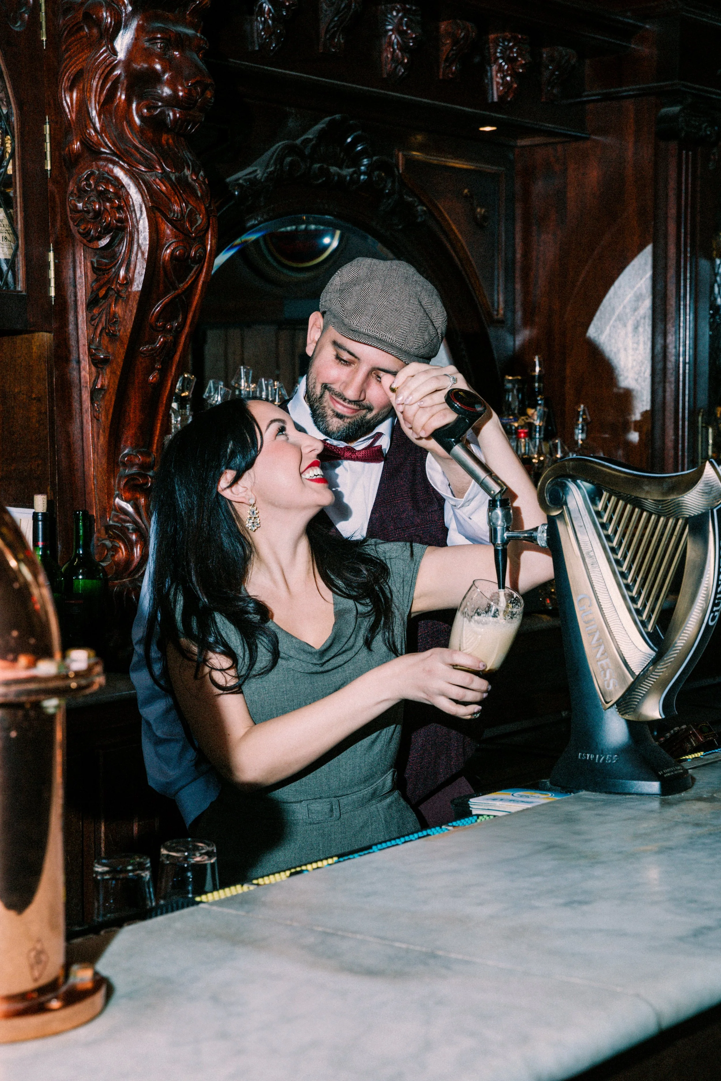 portrait of wedding couple behind bar pouring beer into glass and laughing