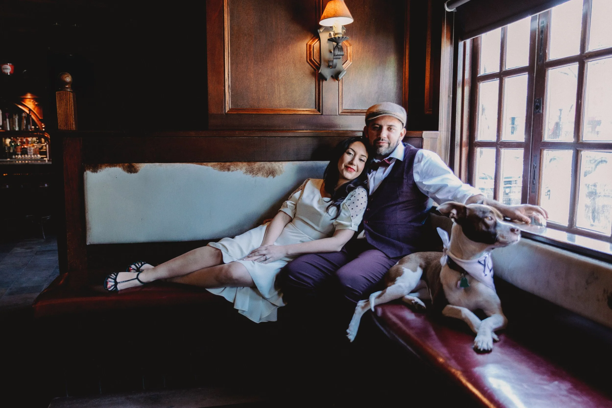 portrait of couple sitting in booth together with dog in a bar in new york