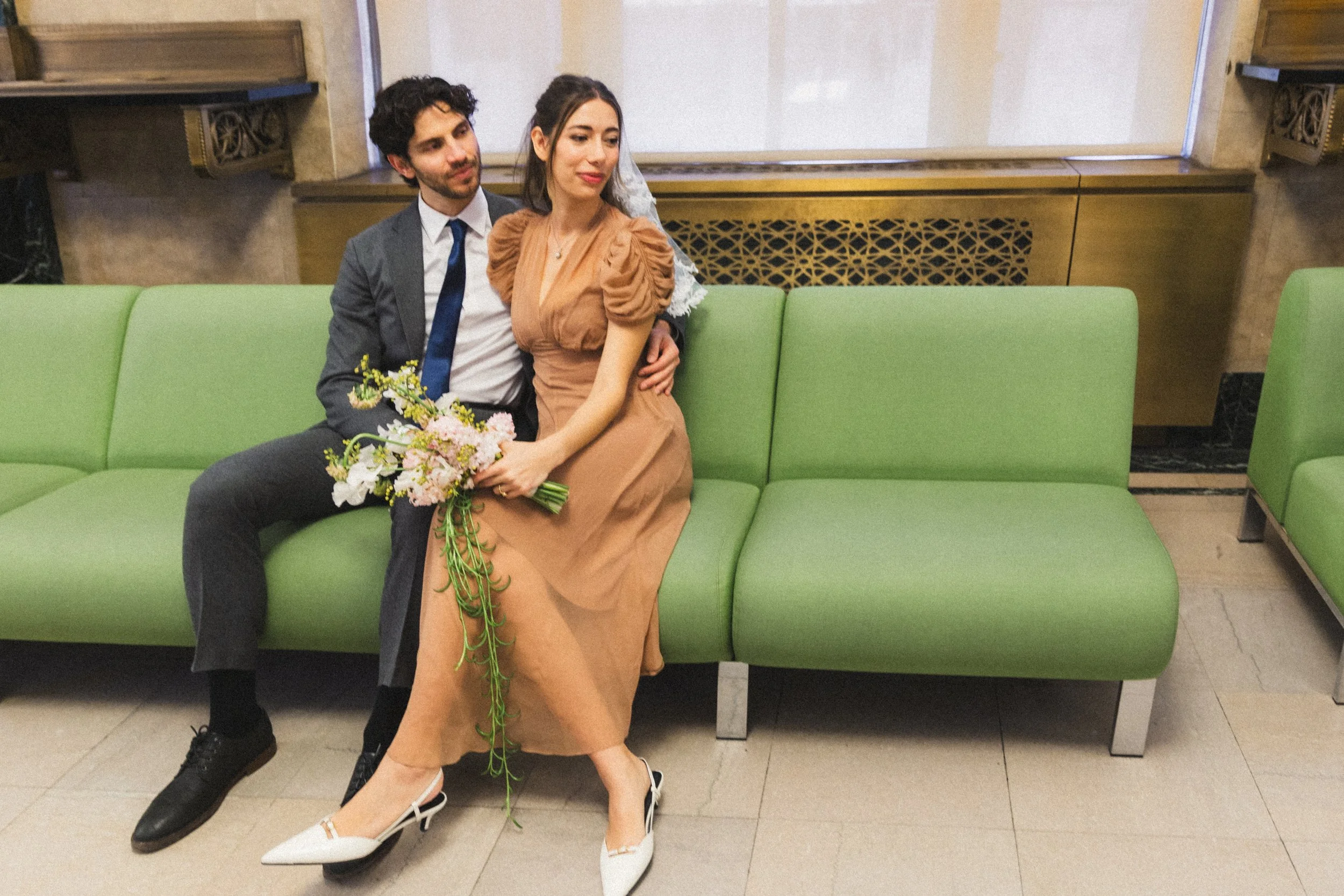 a couple sits in the nyc city hall courthouse waiting for their turn to get married