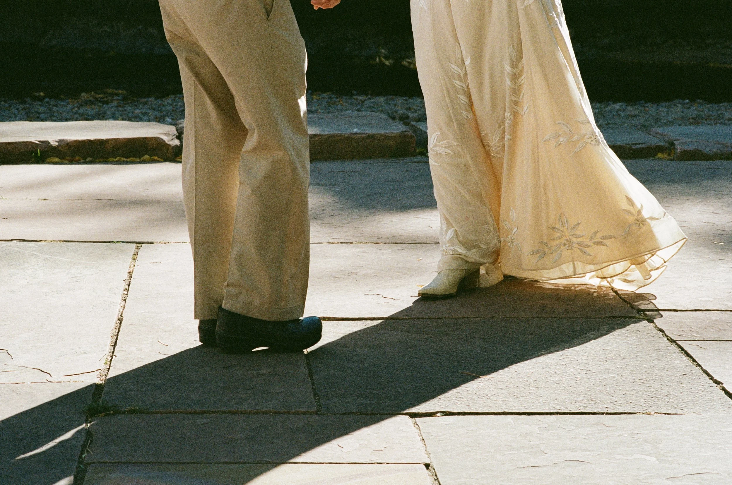 close up of the bottom of wedding dress of bride dancing with father