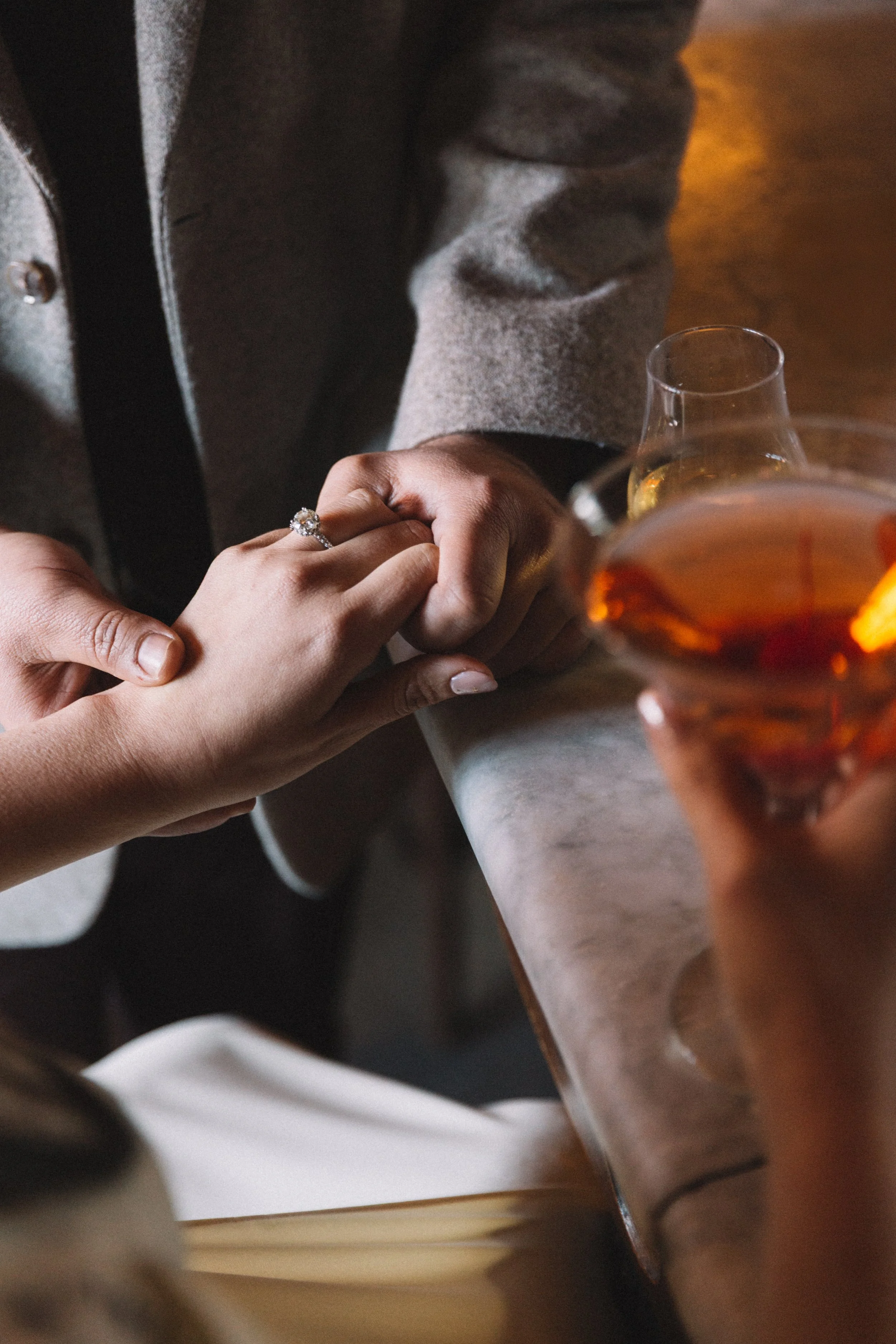 close up photo of a man holding a woman's hand with engagement ring on
