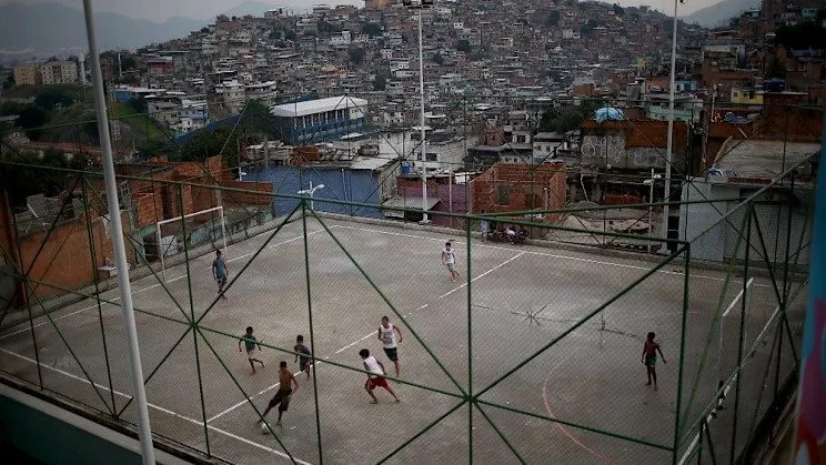 Young kids playing soccer in the streets.