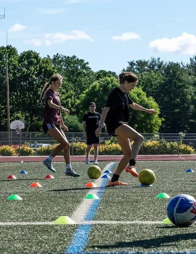 Small group soccer training session with coach overseeing and participating in drills.