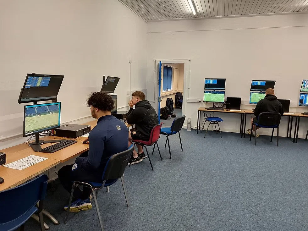 Soccer players reviewing game footage in video analysis session.