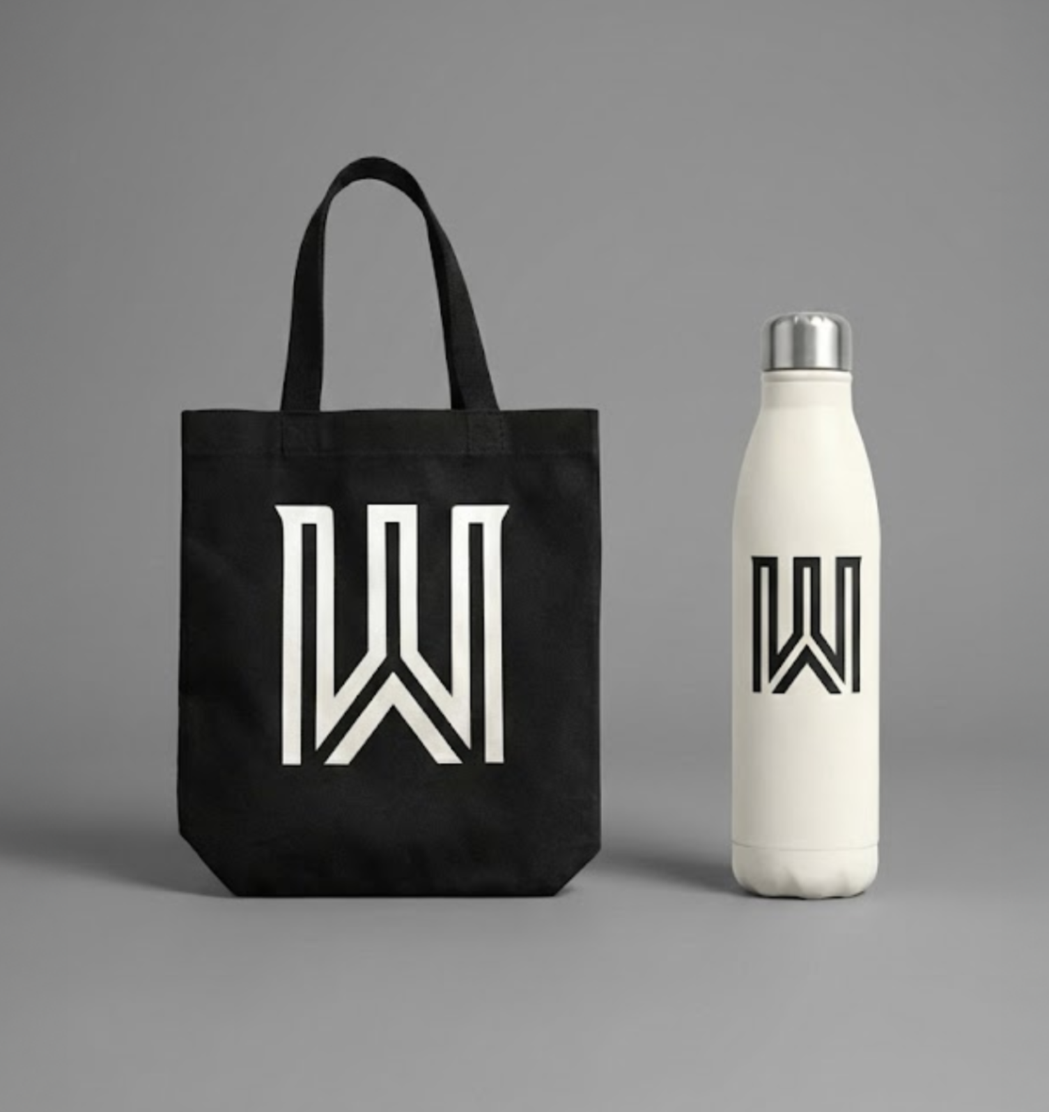 A black tote bag and a white water bottle, both with a matching black geometric logo, against a gray background.