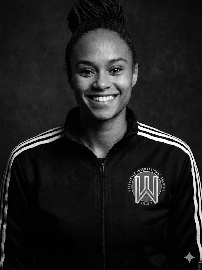 A smiling young woman with braided hair wearing a black jacket with white stripes on the shoulders and a logo that says 'Victusale International Academy' on the left chest, against a dark background.