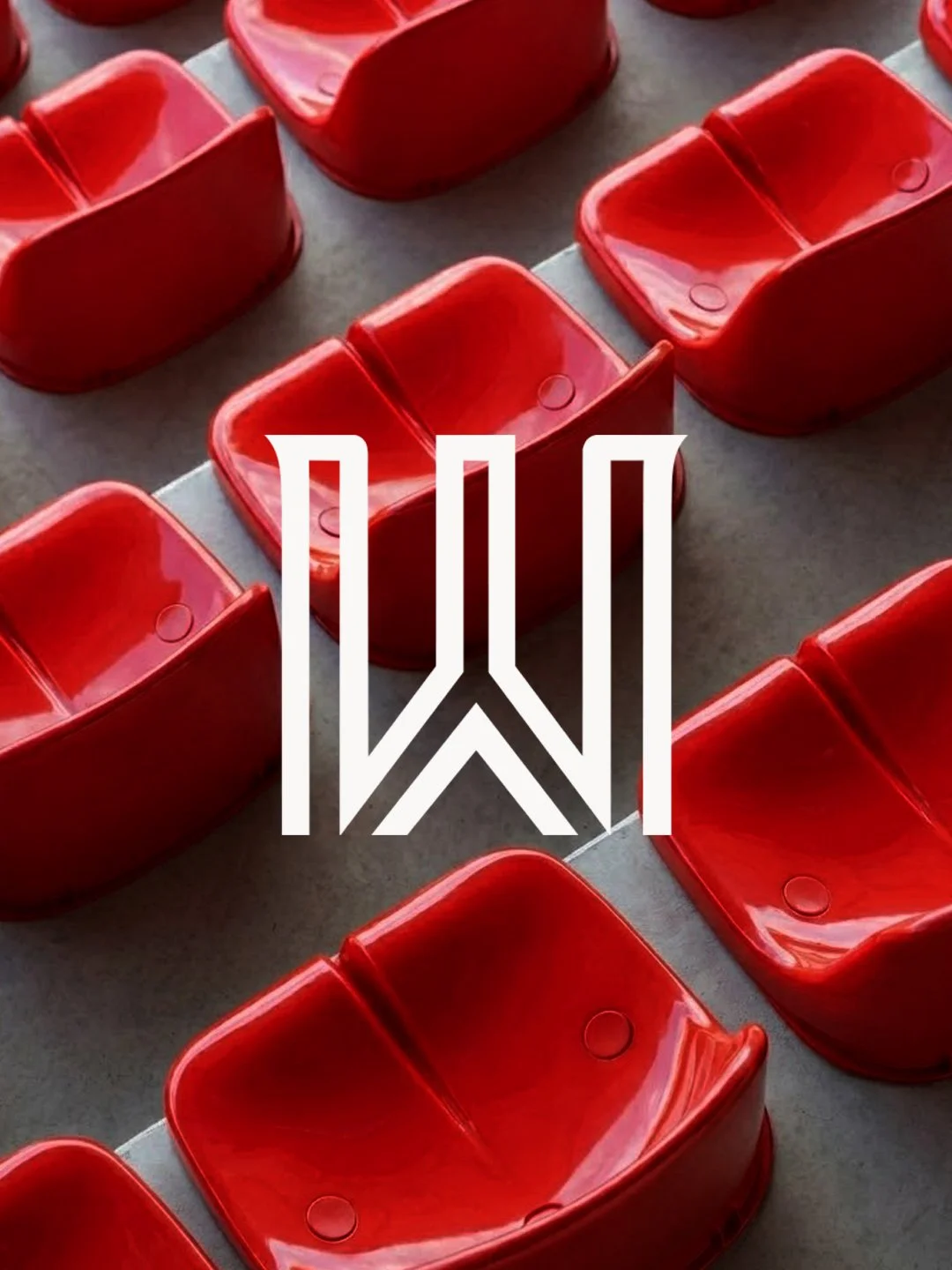 Multiple red plastic seats arranged in rows on a gray surface, with a white geometric logo overlay.