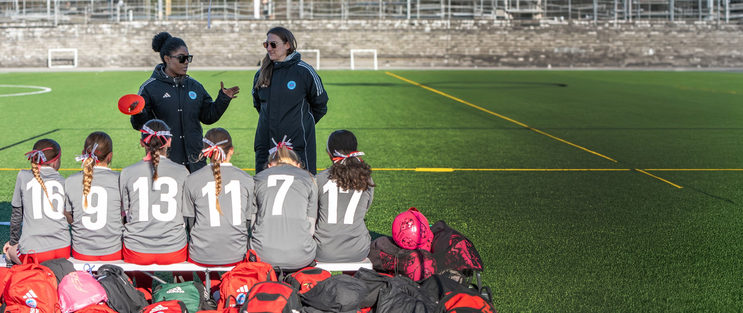 Female soccer players in red uniforms celebrating and high-fiving each other on a soccer field.