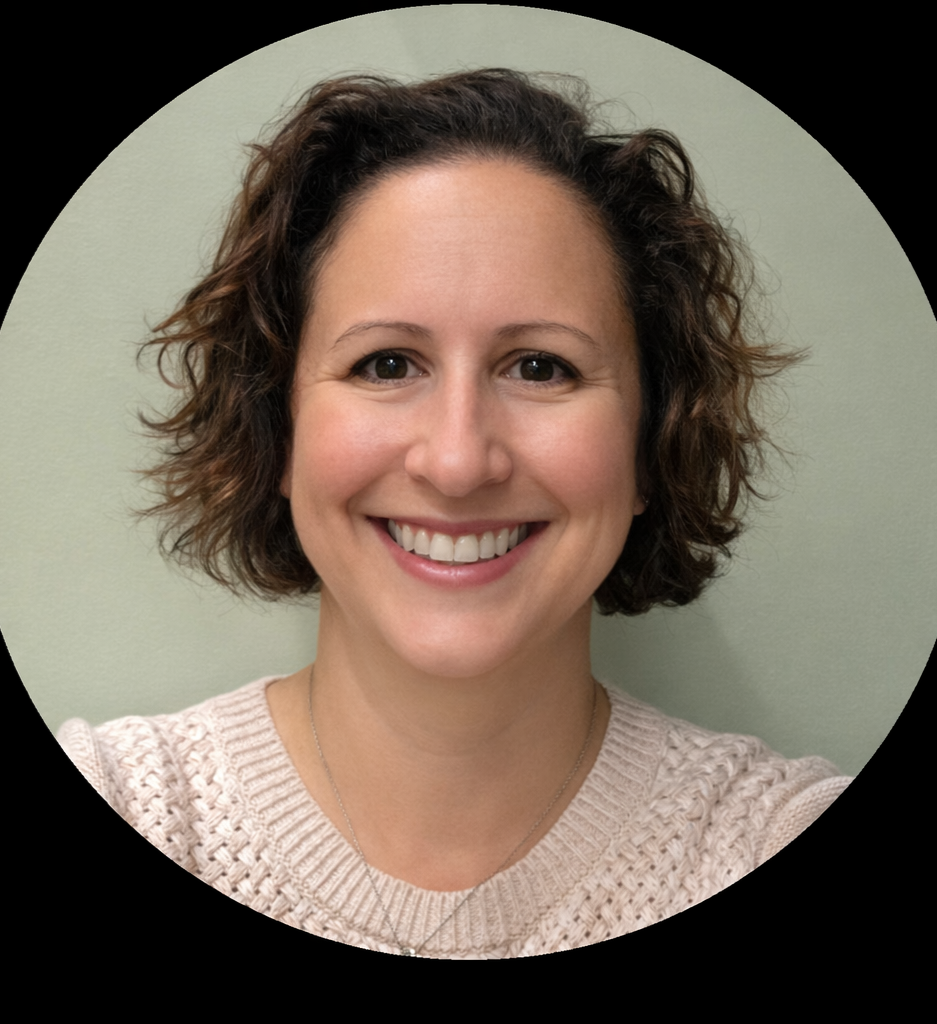 A smiling woman with shoulder-length curly brown hair, wearing a beige knitted sweater and a silver necklace, against a light green background.