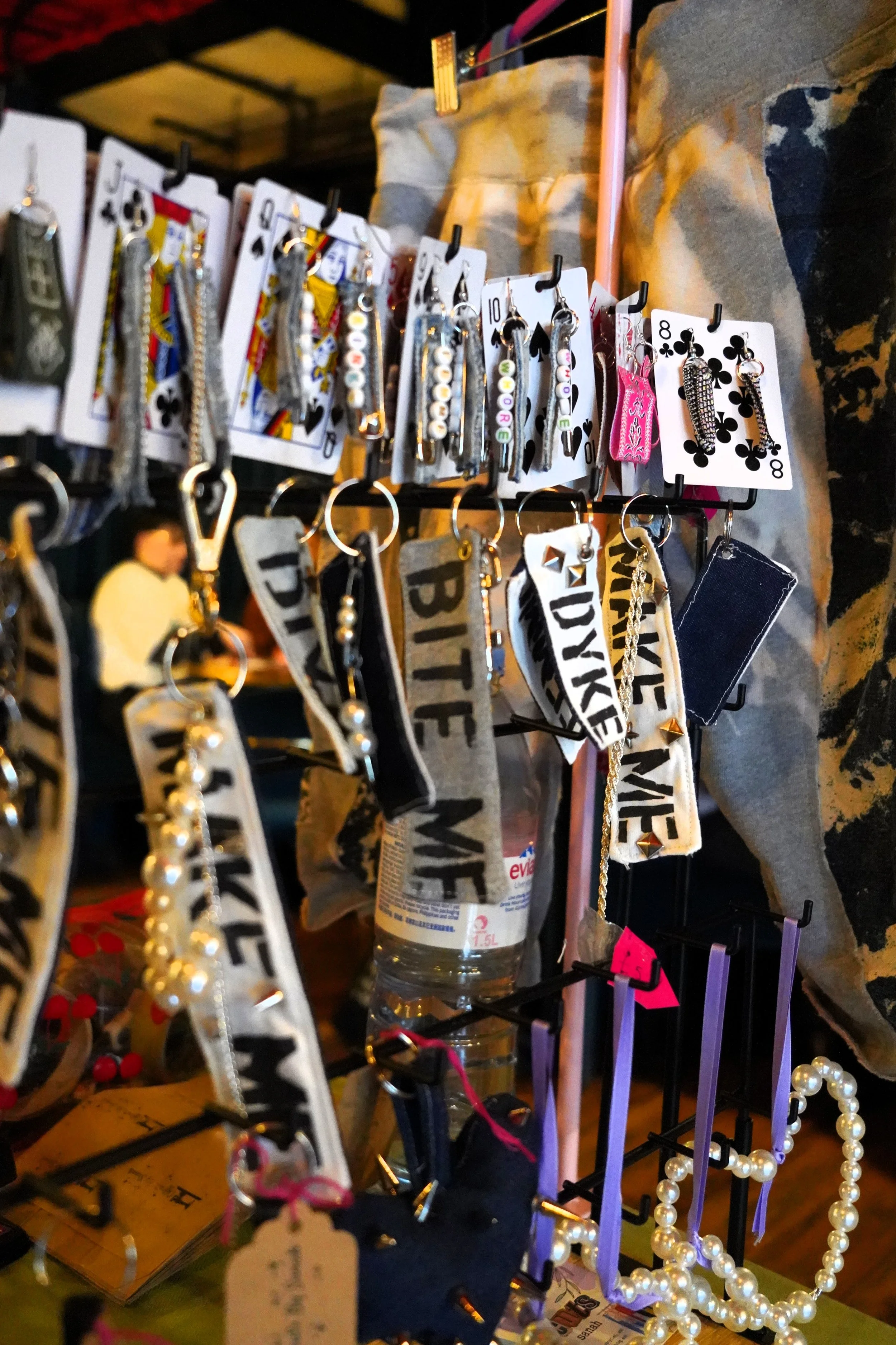 Display of various jewelry and accessories, including earrings, hairbands, and necklaces, hanging on a rack at a market or craft fair.