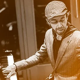 Man wearing glasses and a cap playing a keyboard or piano